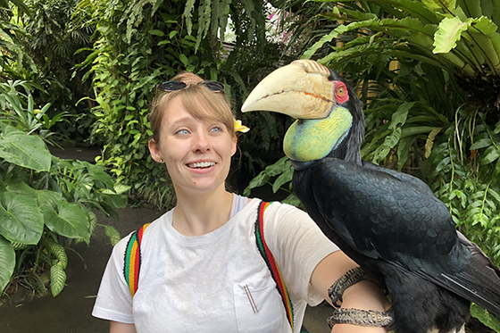 Photo of a Chatham University student in a jungle with a large exotic bird perched on her arm
