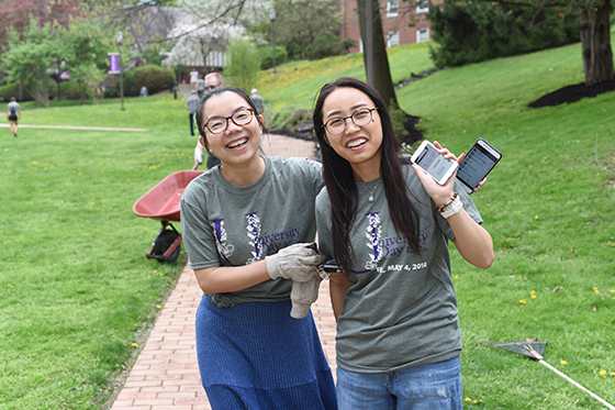 Photo of two international students on Chatham University's Shadyside Campus, pausing while volunteering to plant flowers