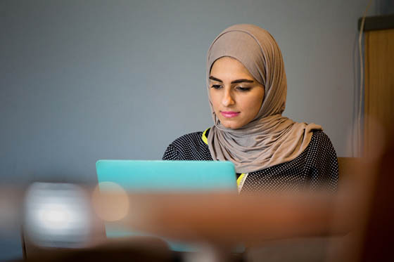 Photo of a student working on her laptop in Cafe Rachel