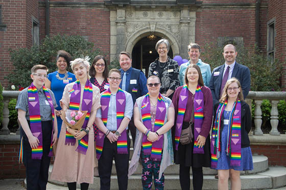 Photo of Chatham University graduates at the Lavender Graduation ceremony, wearing matching purple stoles with a rainbow and pink triangle pattern