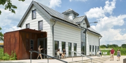 Photo of Chatham University students walking past the white dairy barn with solar panels on the roof at the Eden Hall campus.