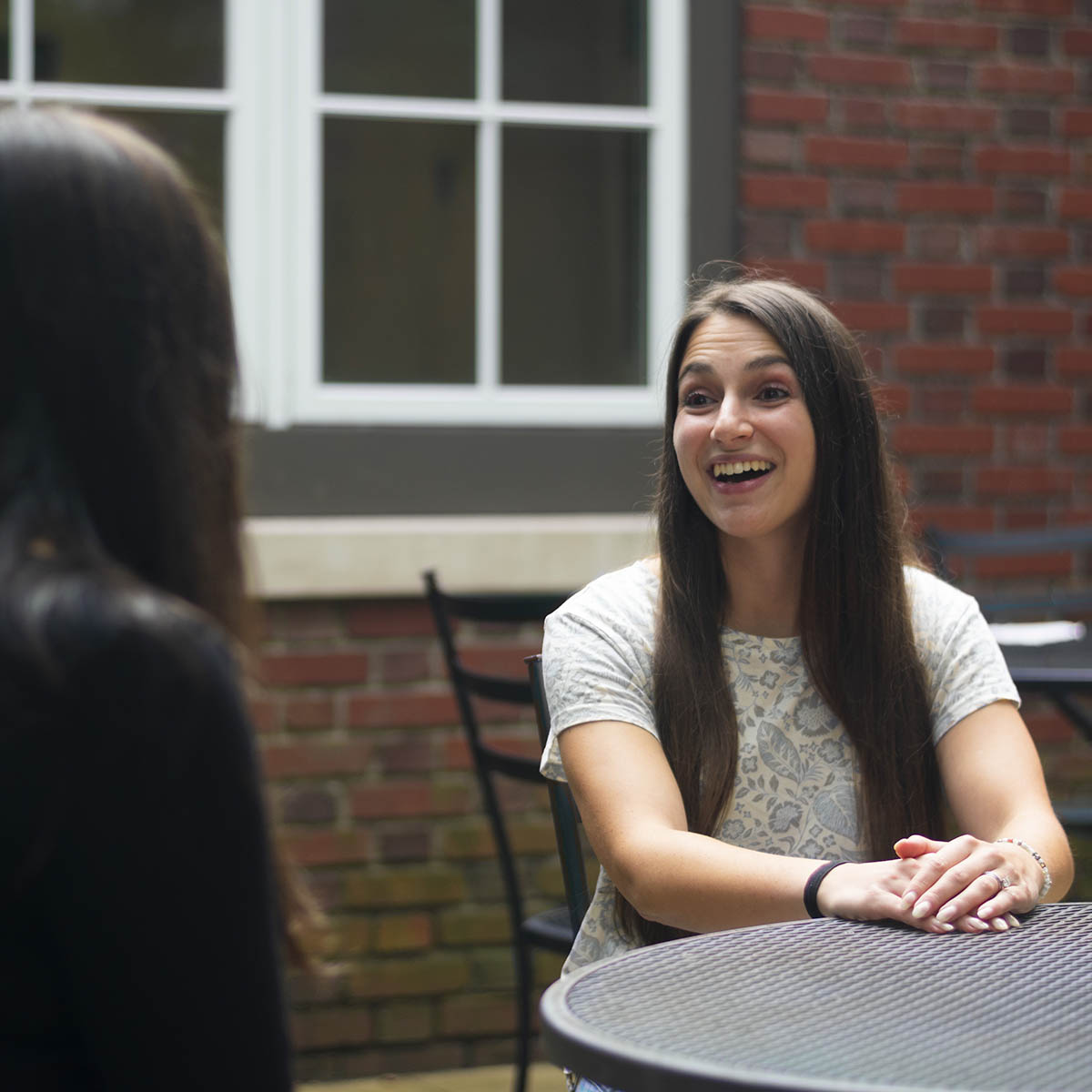 Photo of a success coach smiling and speaking with a student at an outdoor table