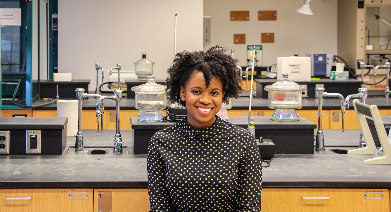Photo of a Chatham University student smiling and posing in a lab