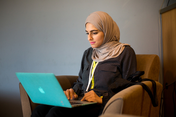 Photo of a young hijabi student working at her laptop in Cafe Rachel