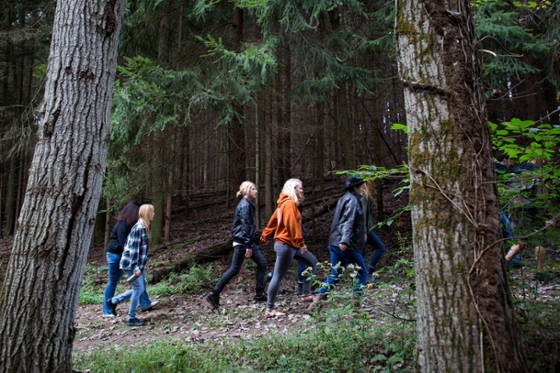 Photo of Chatham University Food Studies students walking through a forest close to Eden Hall campus. 