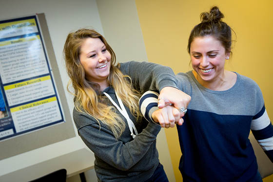 Photo of two young Chatham University students demonstrating physical therapy techniques.