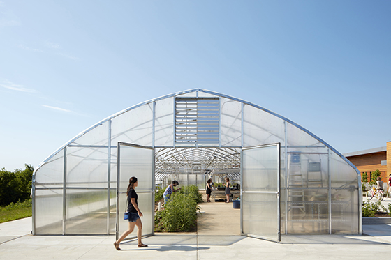 Photo of a student walking past the greenhouse at Chatham University's Eden Hall Farm. 