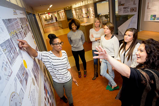 Photo of a Chatham University student presenting her work to a group of peers