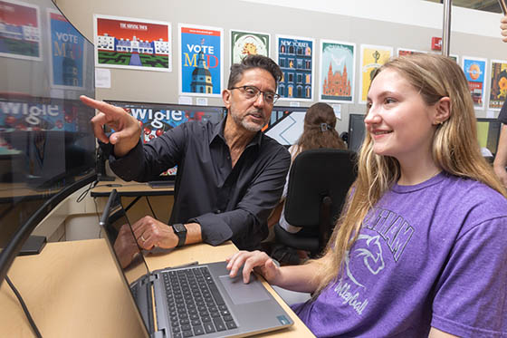 Mark Bender works with a student at a computer in the Art & Design Center