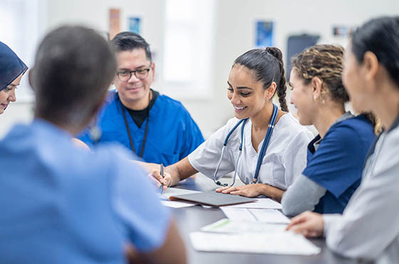 Photo of a Chatham University student watching an instructor demonstrate a procedure on a model of an adult