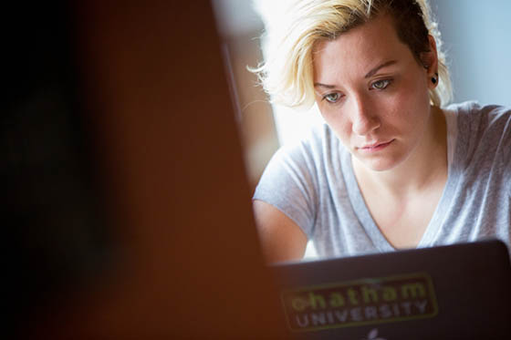 Photo of a Chatham University student looking at her laptop in Cafe Rachel.