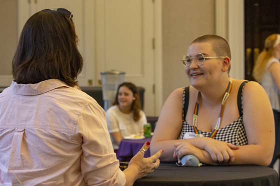 Photo of a middle-aged woman speaking to a young college student at an event