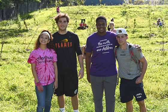 Photo of four Chatham University students posing with arms wrapped around each other at Eden Hall Farm. 