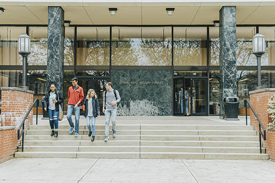 Group of four Chatham students walking down the steps of library