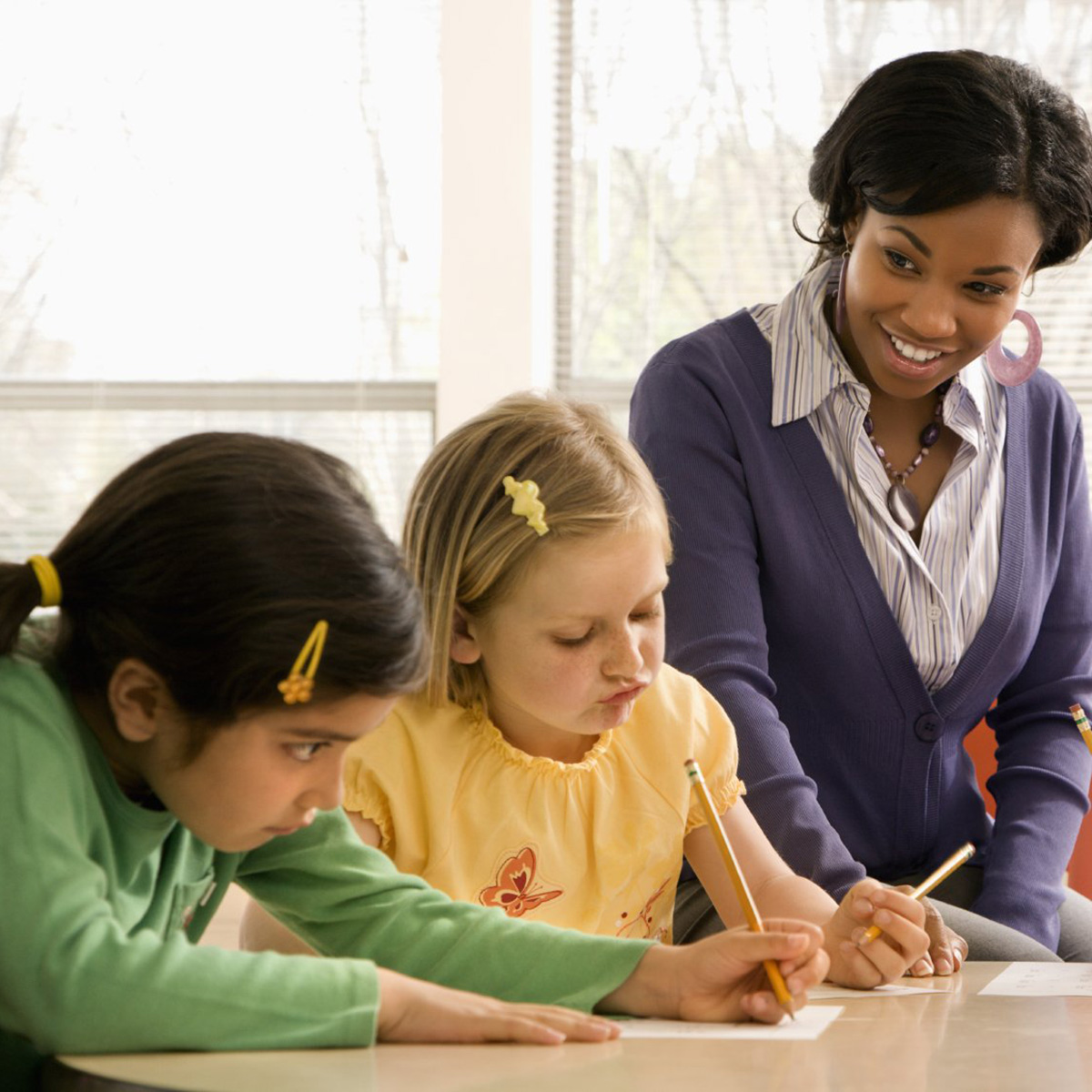 Photo of a teacher helping students working at a desk