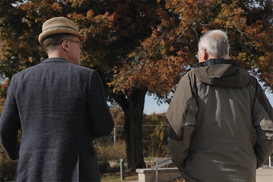 Photo of two men walking away from the camera, conversing on Eden Hall Campus