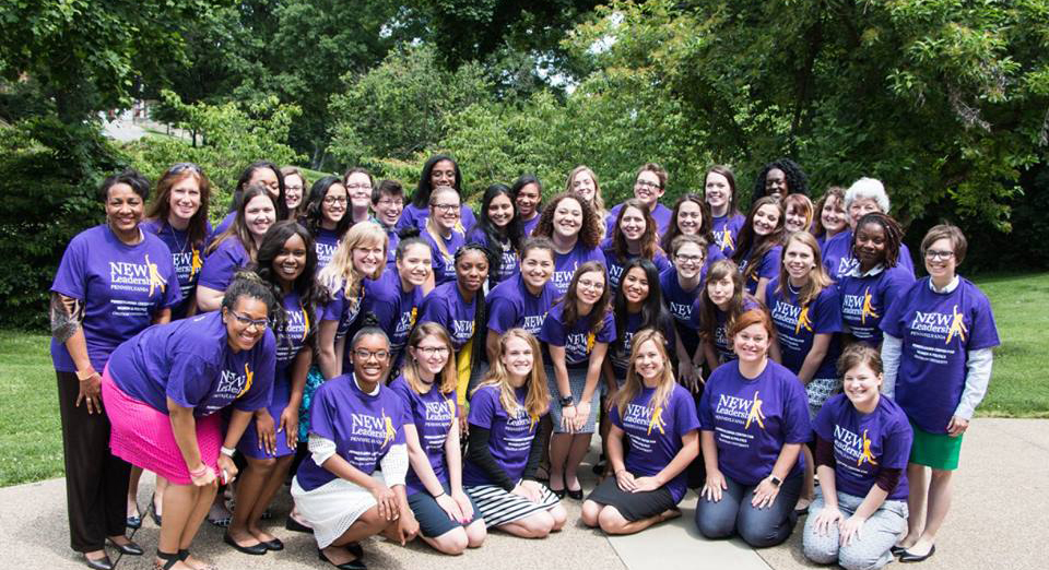 Photo of a group of women posing outside, all in purple New Leadership t-shirts