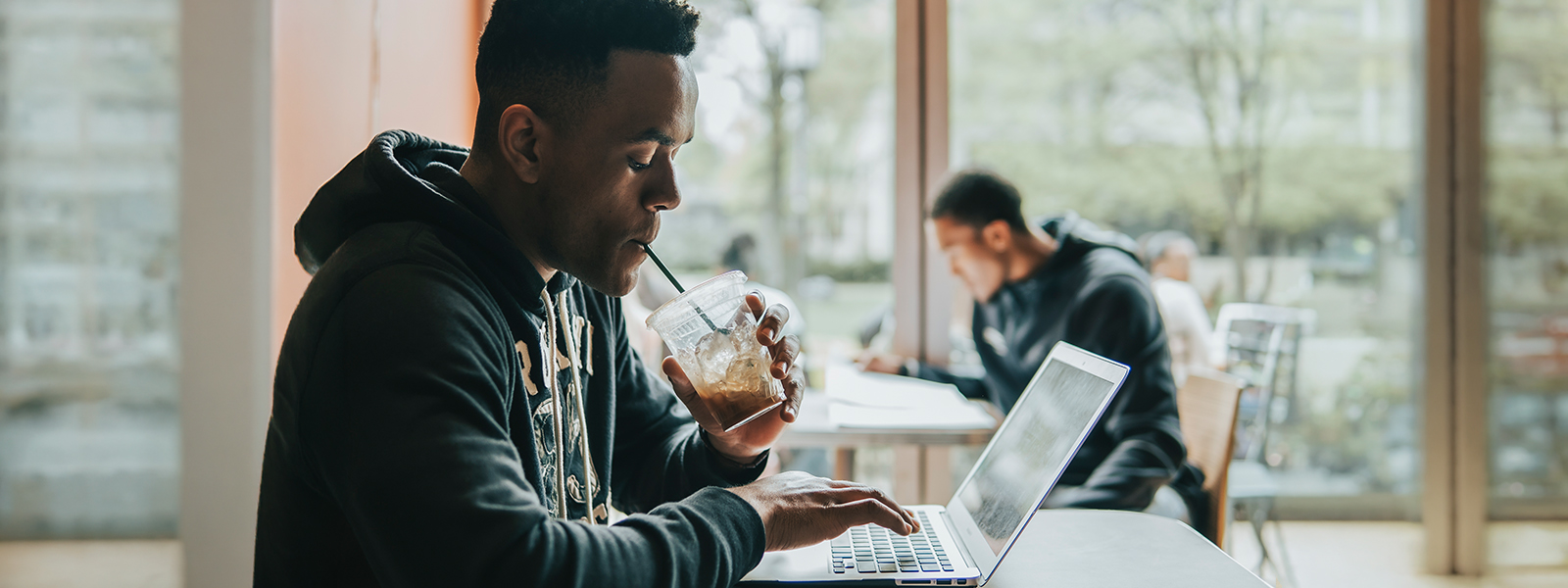 Chatham student works on laptop and drinks coffee in Café Rachel