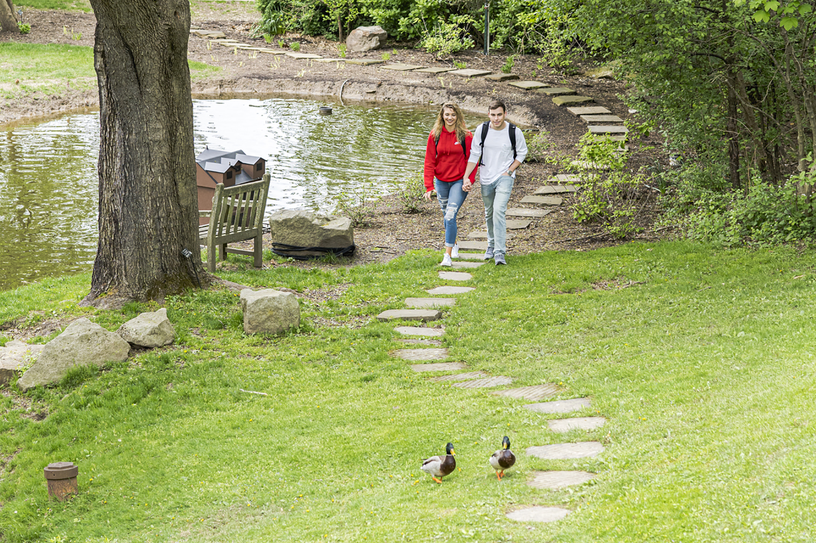 Photo of two Chatham University students walking past on the pond on Shadyside Campus