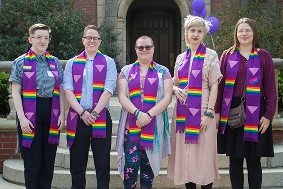 Photo of a group of Chatham University students wearing graduation stoles with rainbow LGBTQ+ representation, posing together for a photo. 